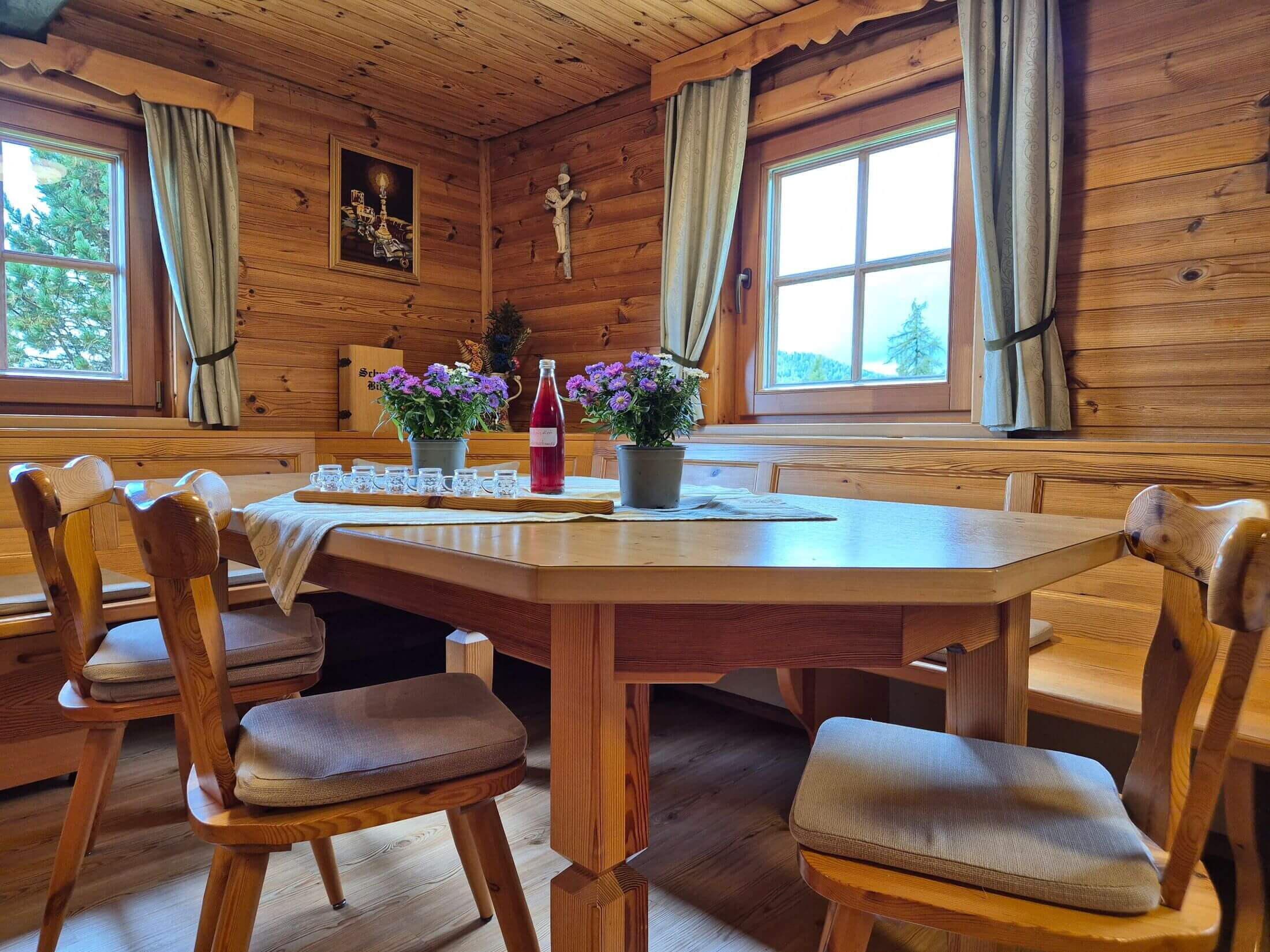 Die Küche und daneben der Esstisch mit Sitzecke dedeckt mit Zirbenschnaps und Schnapsgläser zum anstoßen.