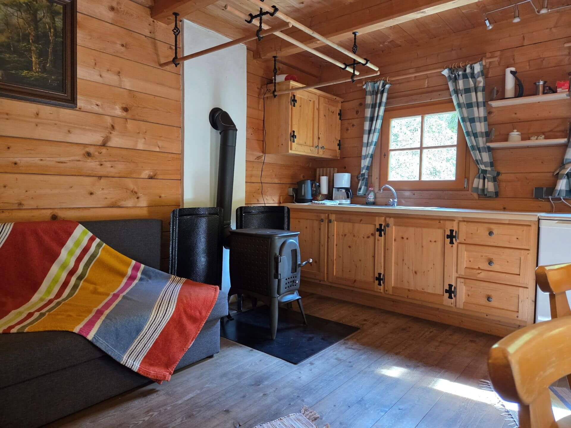 Die gemütliche Ecke in der Mühlenhütte mit Couch und Holzofen.