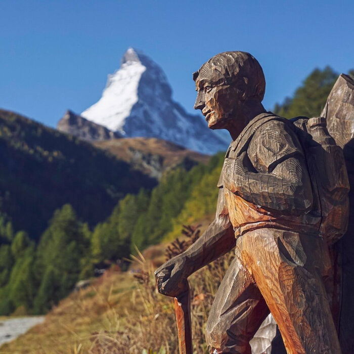 In den Bergen ist eine Lebensgroße geschnitzte Wanderfigur aufgestellt, eine wahre Kunst.