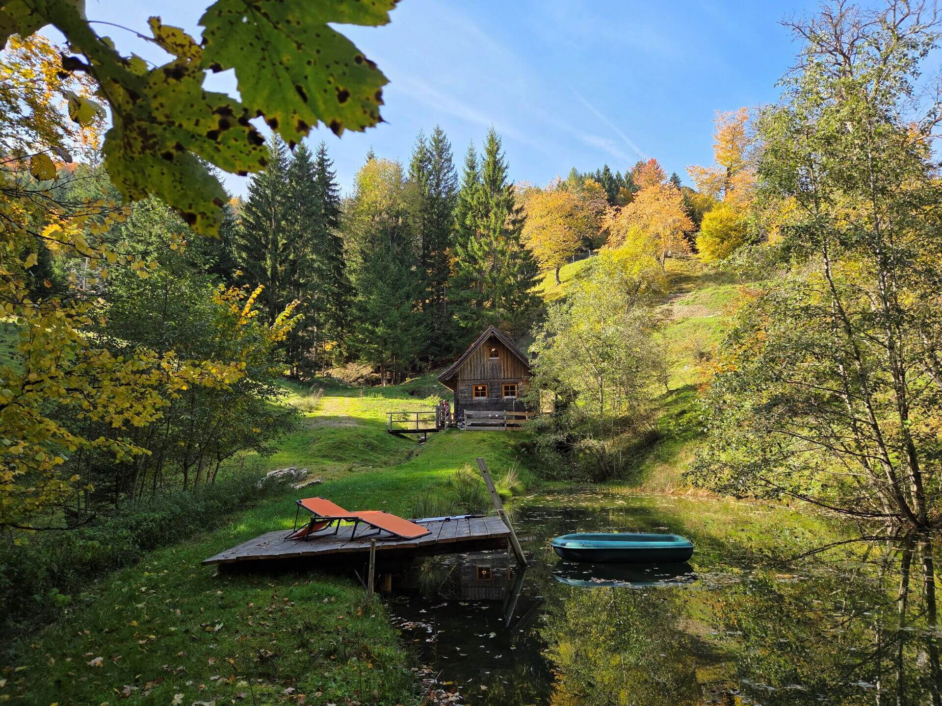 Der Teich bei der Mühlenhütte, am Steg die Liege und im Wasser das Boot.