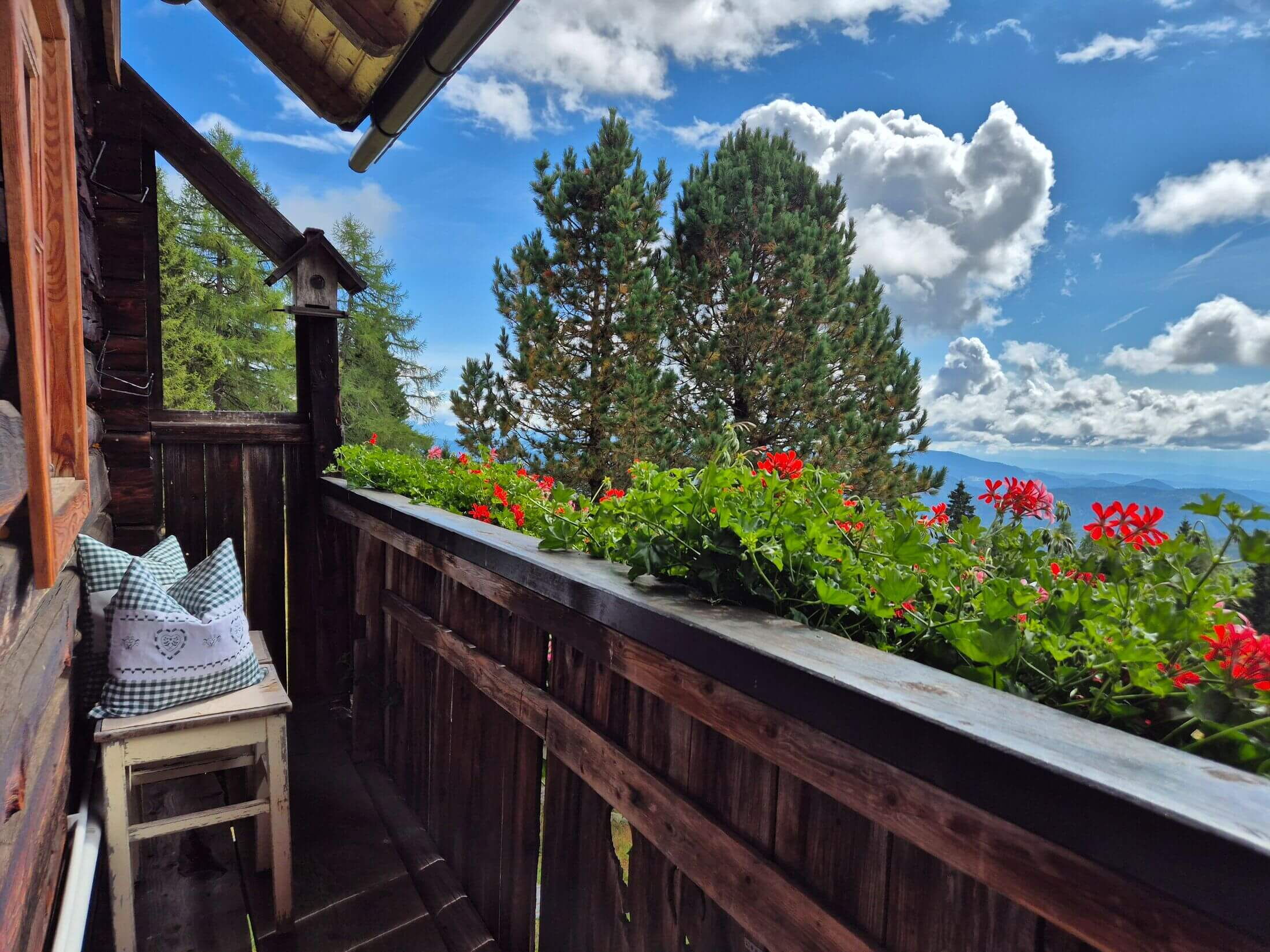 Der Balkon mit schönen Balkonblumen und Sitzgelegenheit mit Bergblick auf der Pietschacher Almhütte