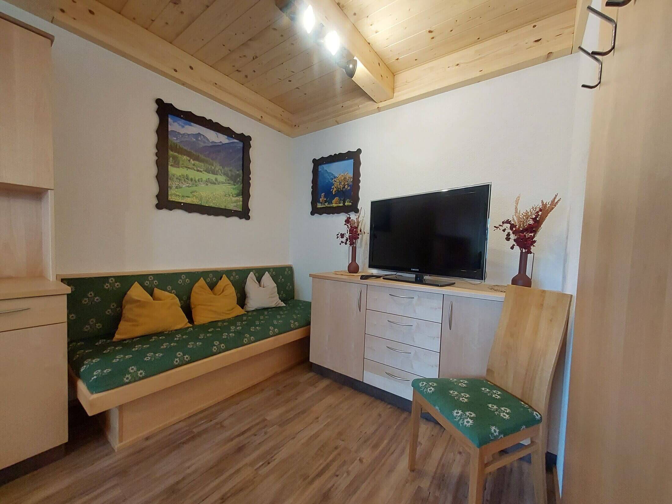 Die Wohnzimmerecke in der AlpenSteinbock-Hütte mit Sitzgelegenheit und Fernseher.