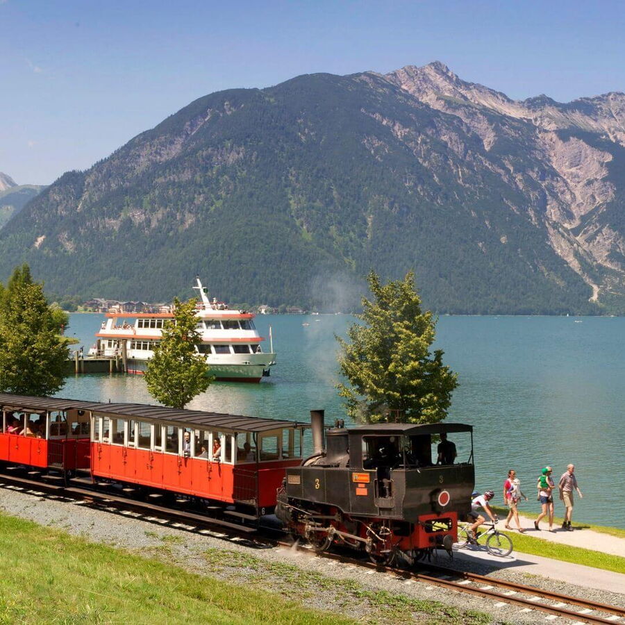 Die Achenseebahn und im Hintergrund der kristallklare Achensee und der Dampfer.